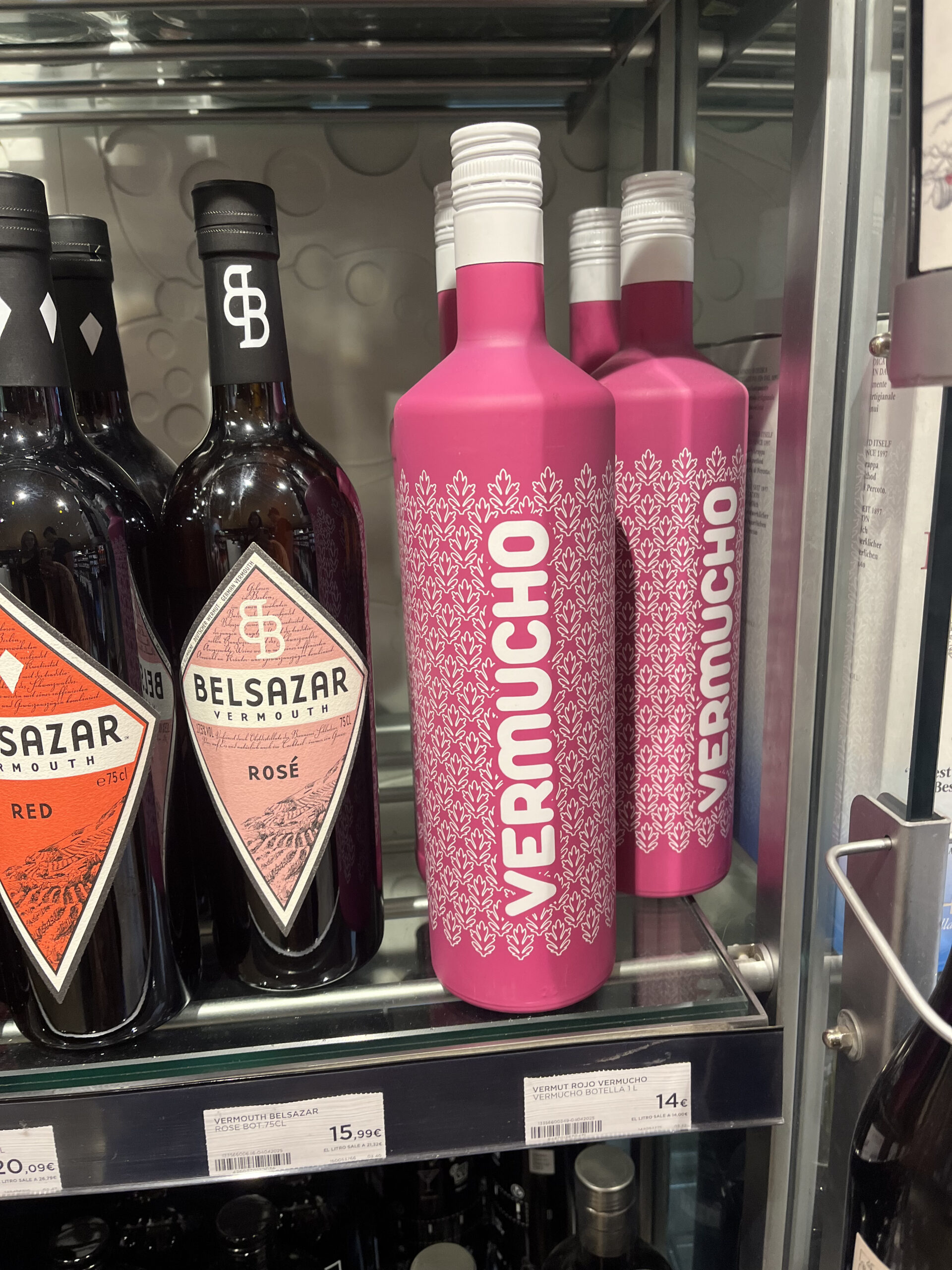 Botella rosa intensa de vermut VERMUCHO con diseño minimalista y tipografía vertical blanca.
