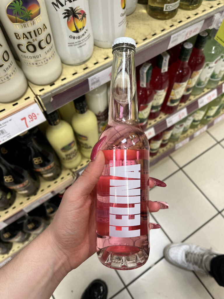 Botella transparente de bebida rosa con logotipo vertical blanco FELINA, diseño tipográfico moderno y limpio.